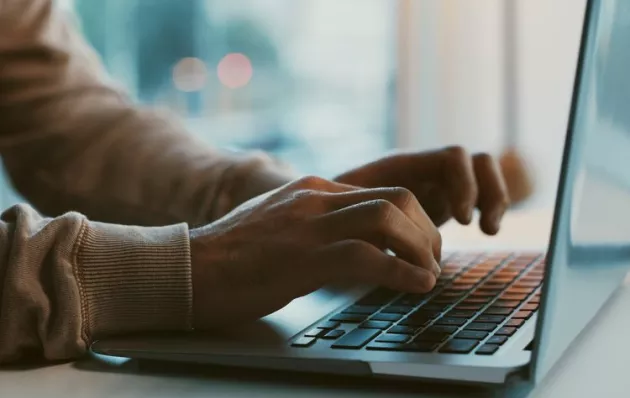 Hands typing on a laptop