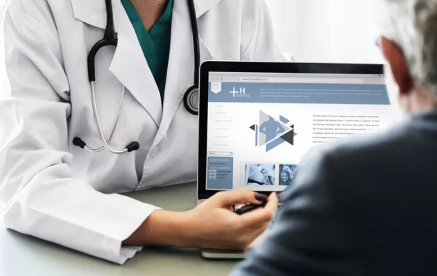 Photo of a doctor showing info on a laptop